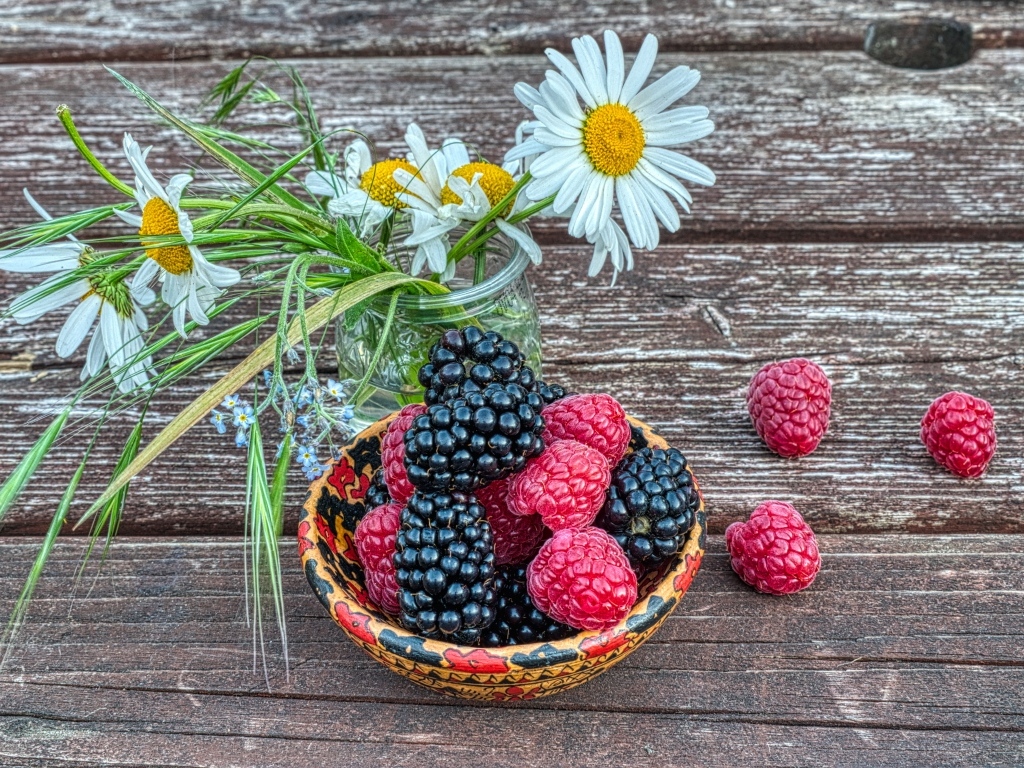 Ягоды черники и малины на столе с ромашками