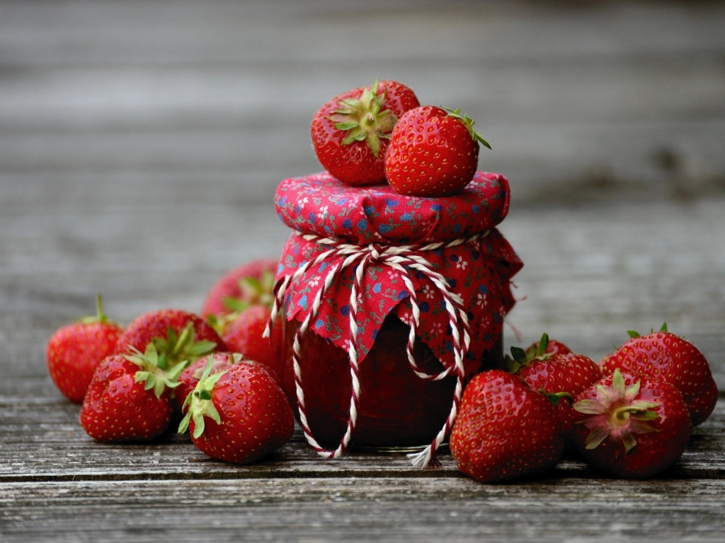 Банка джема на столе со свежими ароматными ягодами клубники