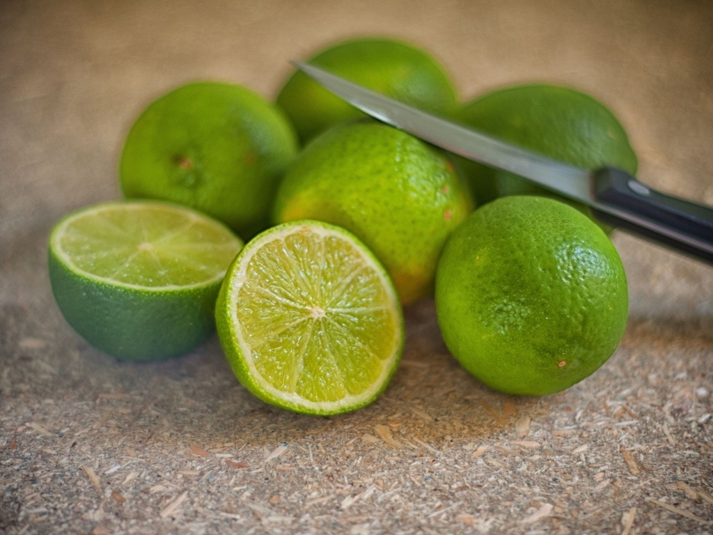 Много зеленых лаймов на столе с ножом