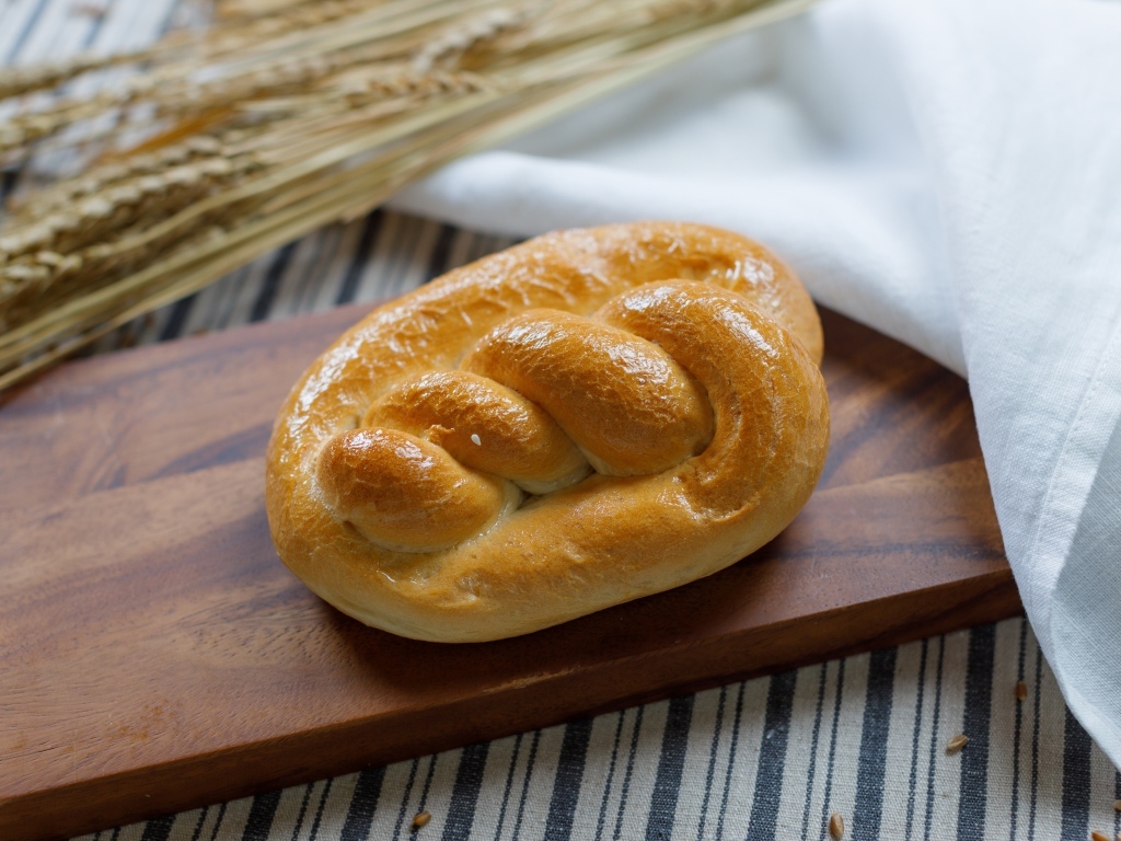 Булочка на столе с колосьями пшеницы