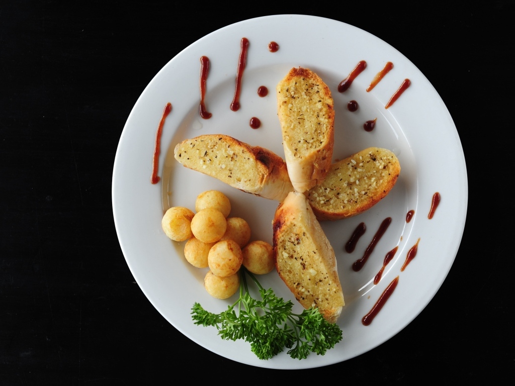 Чесночный хлеб на тарелке с картофельными шариками