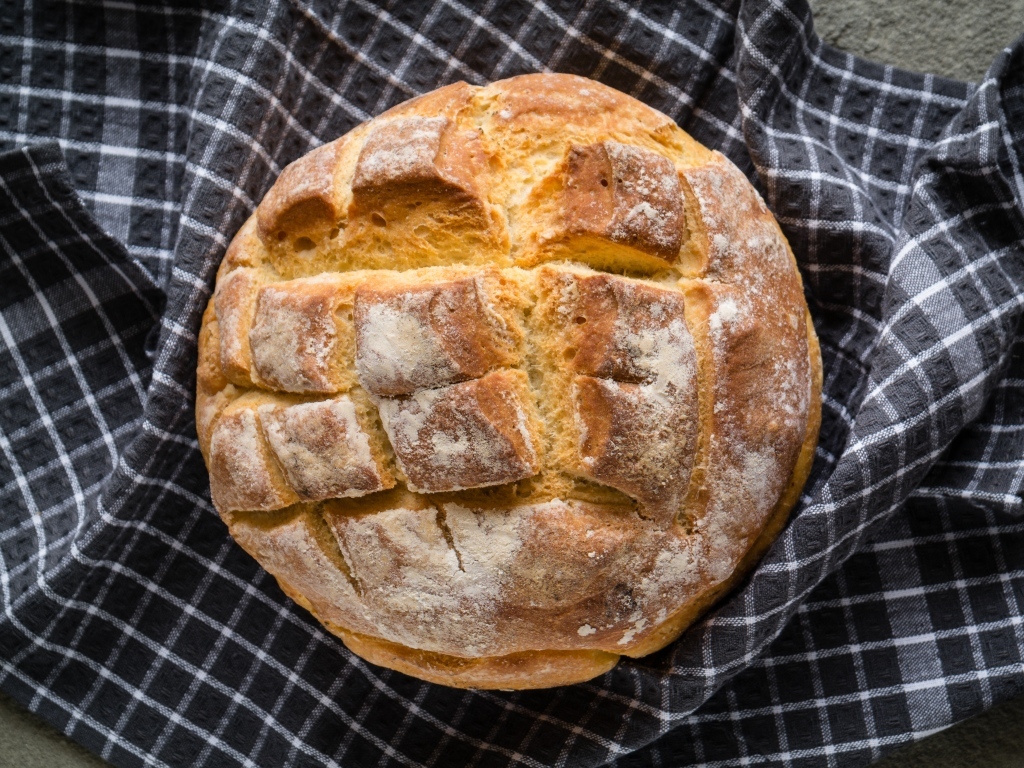 Круглый хрустящий хлеб на столе со скатертью