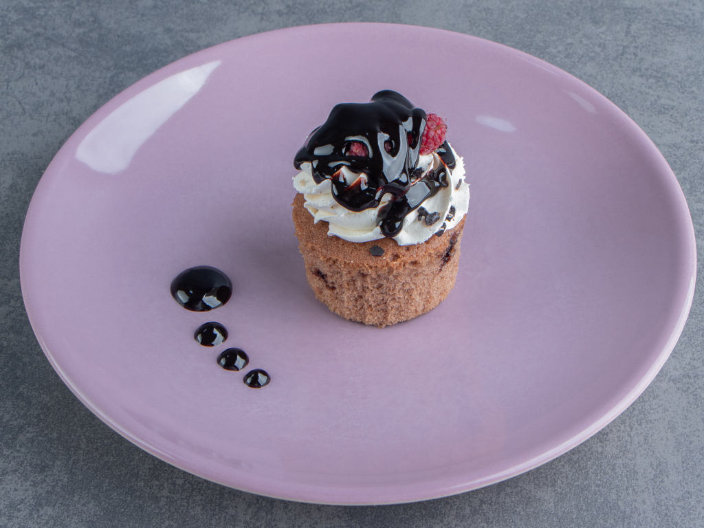 Маффин с шоколадным топпингом на большой тарелке