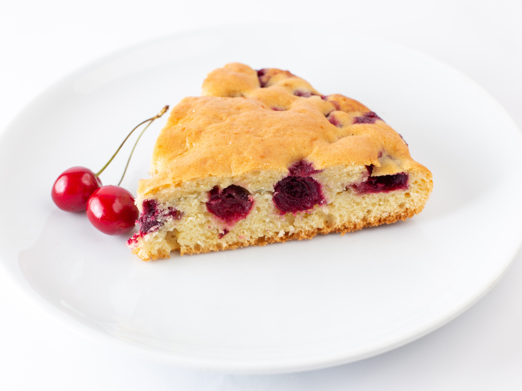Кусок вишневого пирога с ягодами на тарелке