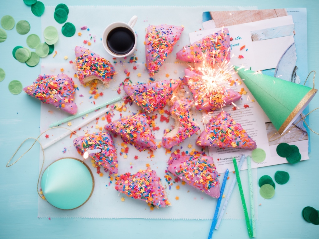 Кусочки торта в розовой глазури на столе с праздничным декором