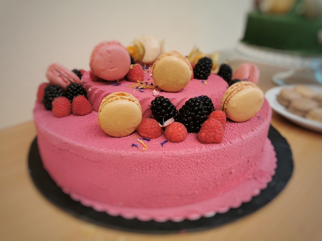 Розовый торт украшен печеньем и ягодами