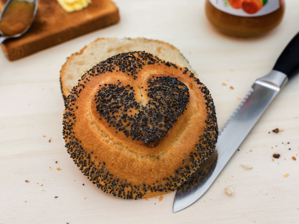 Булочка с маком с нарисованным сердцем на столе