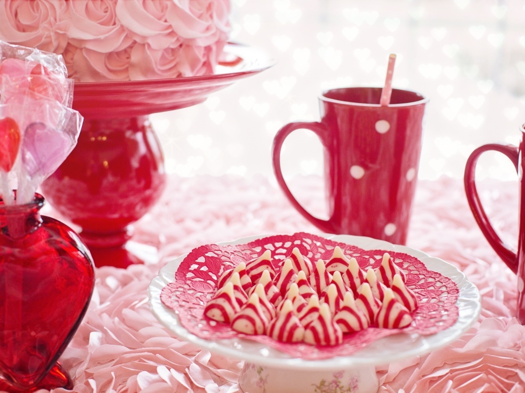 Сладкие розовые конфеты на столе с чаем и тортом
