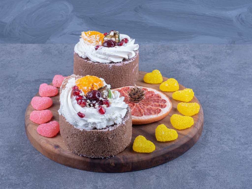 Два пирожных на деревянной доске с мармеладными конфетами