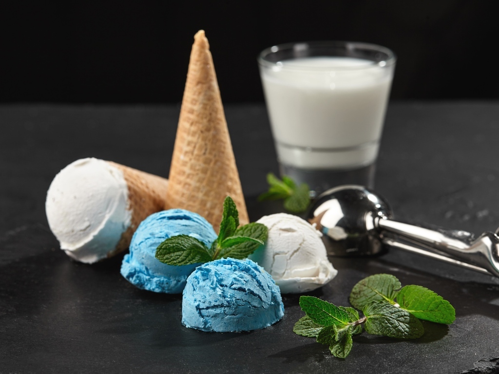 Вафельный рожок с шариками мороженого, мятой и молоком на столе