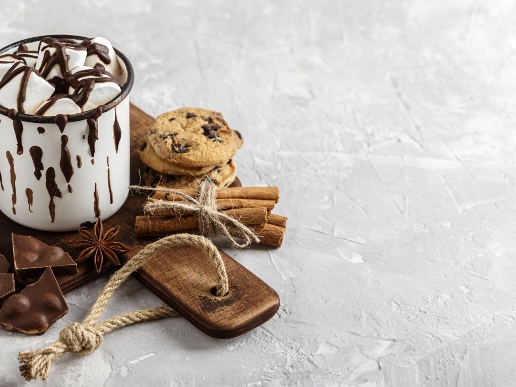 Горячий шоколад с маршмеллоу на столе с печеньем и конфетами