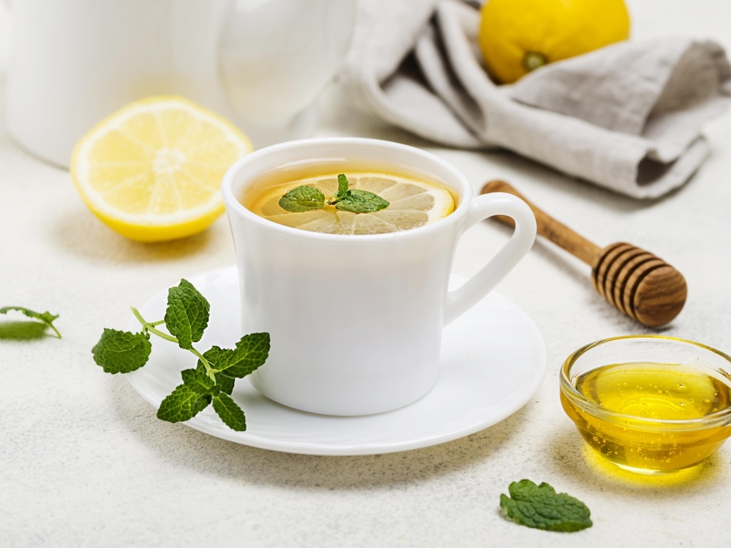Белая кружка с чаем на столе с медом и лимоном