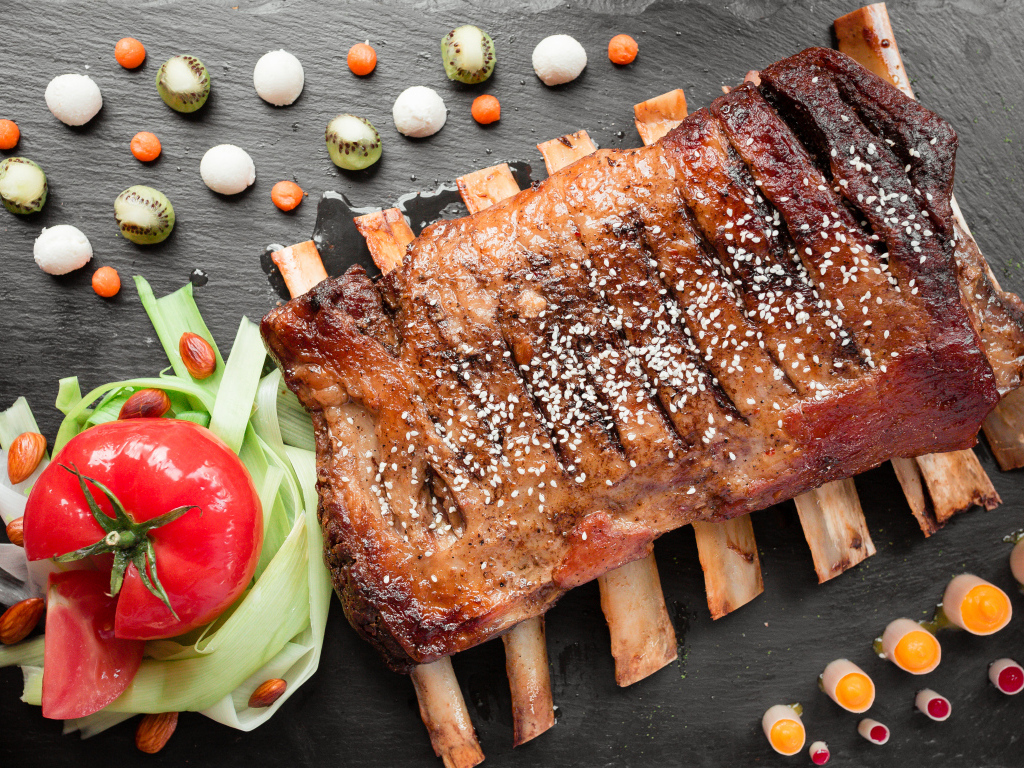 Свиные ребра на столе с овощами