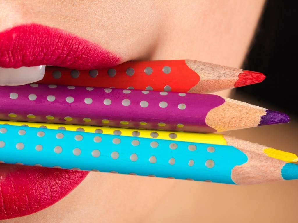 Разноцветные карандаши в губах у девушки