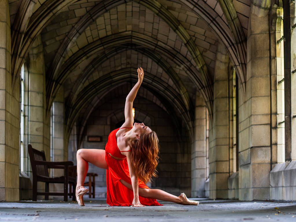Девушка в красном наряде танцует в здании