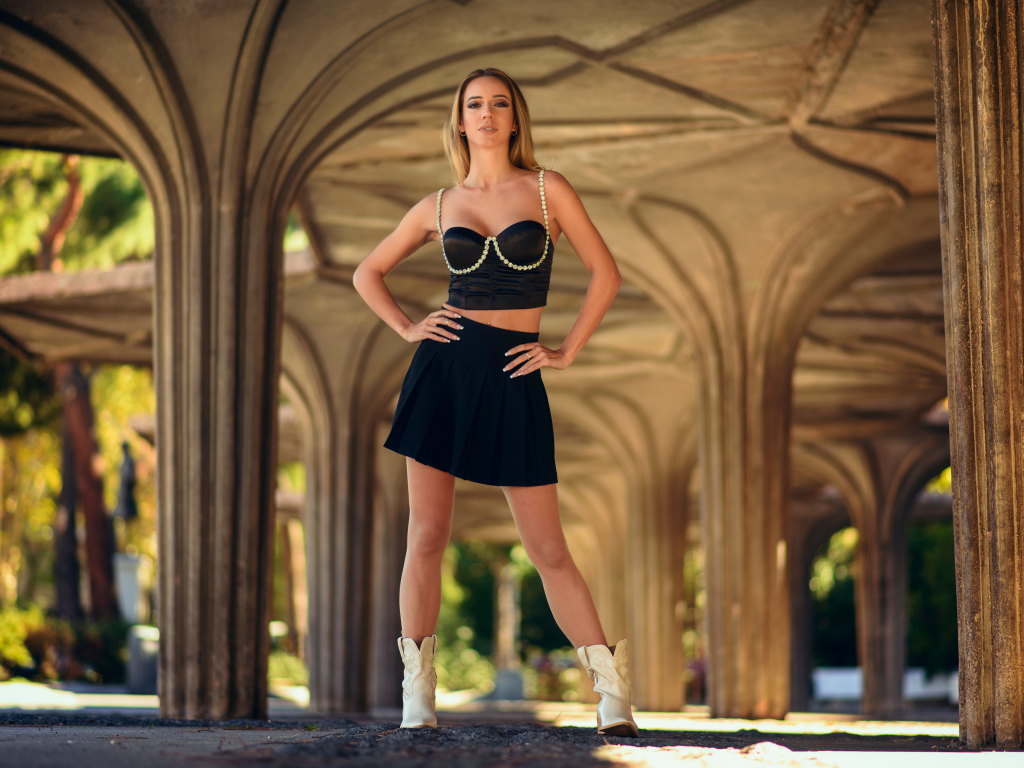 Девушка в короткой черной юбке стоит у здания