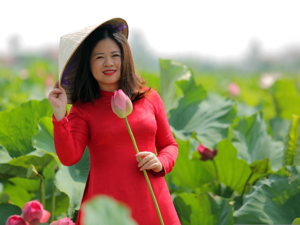 Девушка азиатка в красном платье у цветов лотоса