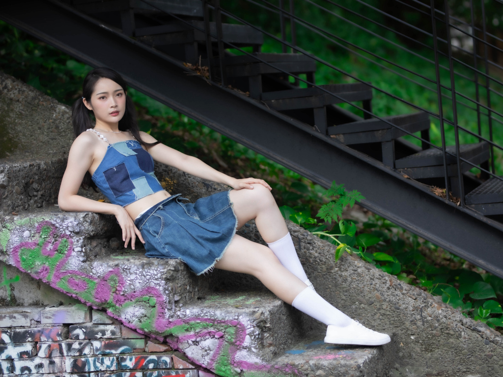 Девушка азиатка в юбке лежит на лестнице