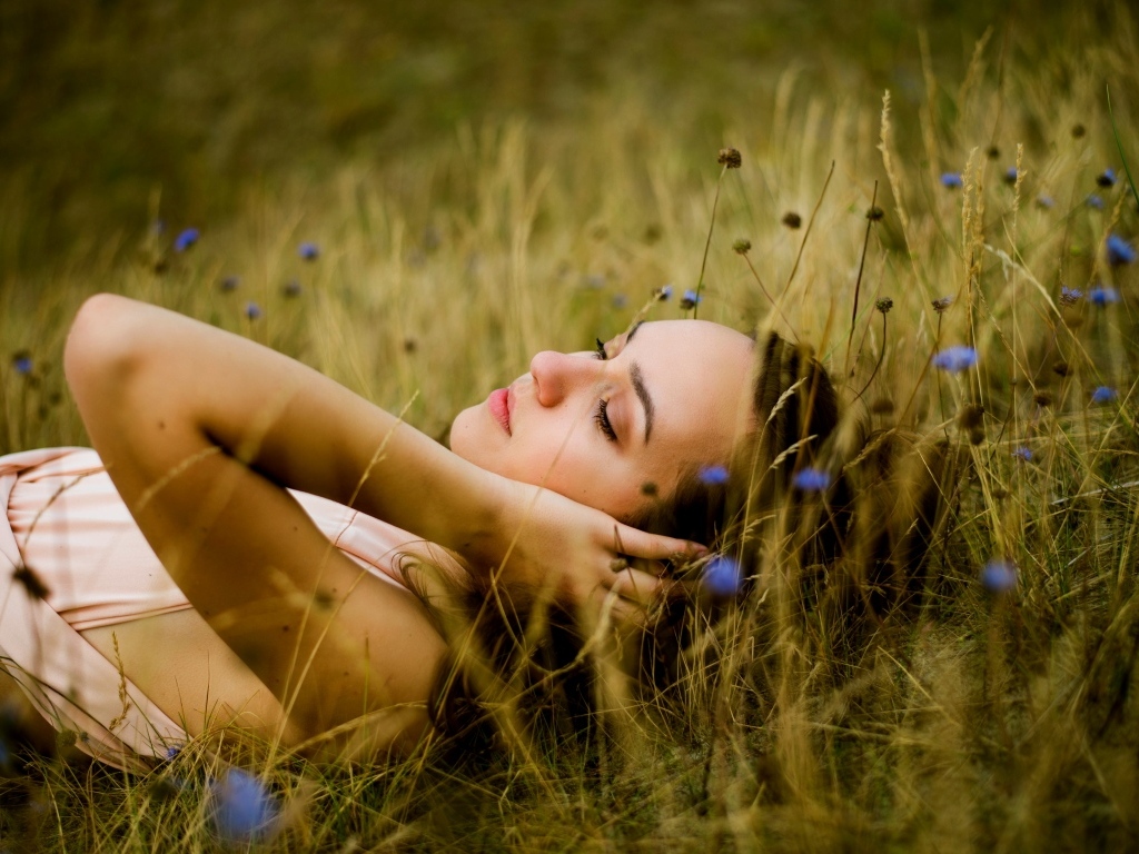 Милая девушка лежит на траве на поле