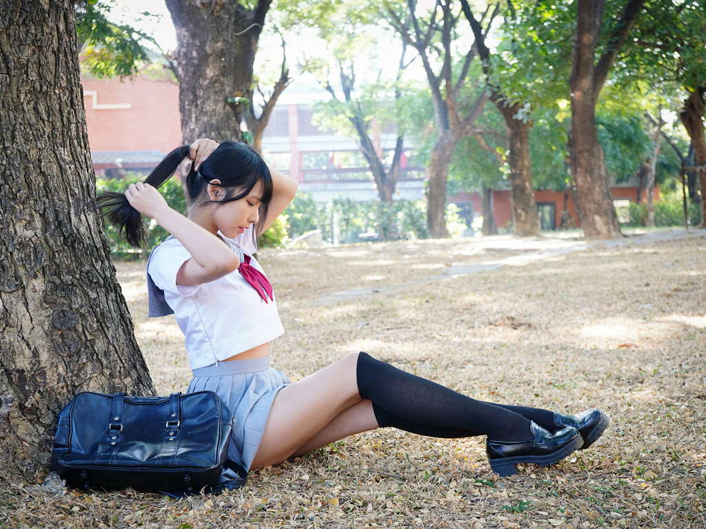 Милая молодая девушка студентка сидит под деревом в парке