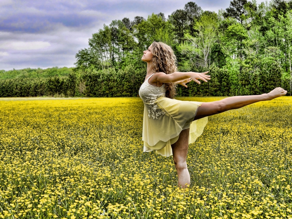 Девушка танцует на поле с желтыми цветами
