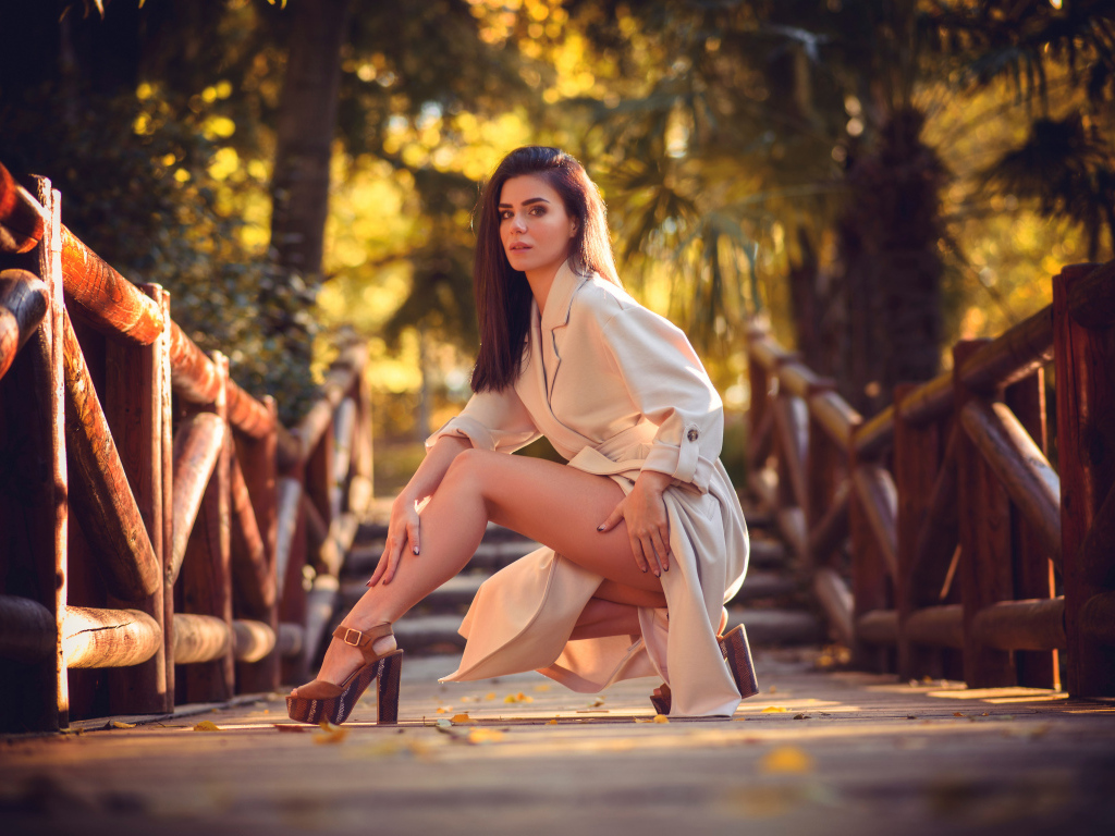 Девушка в пальто на мосту в парке 