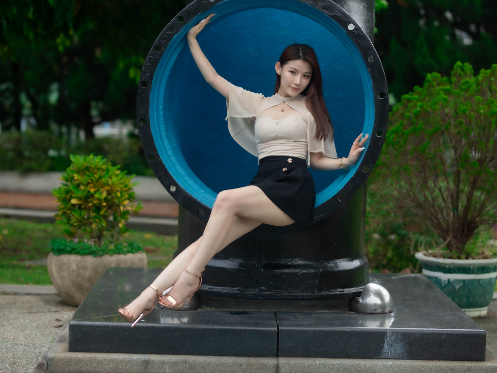 Стройная длинноногая азиатка сидит в трубе