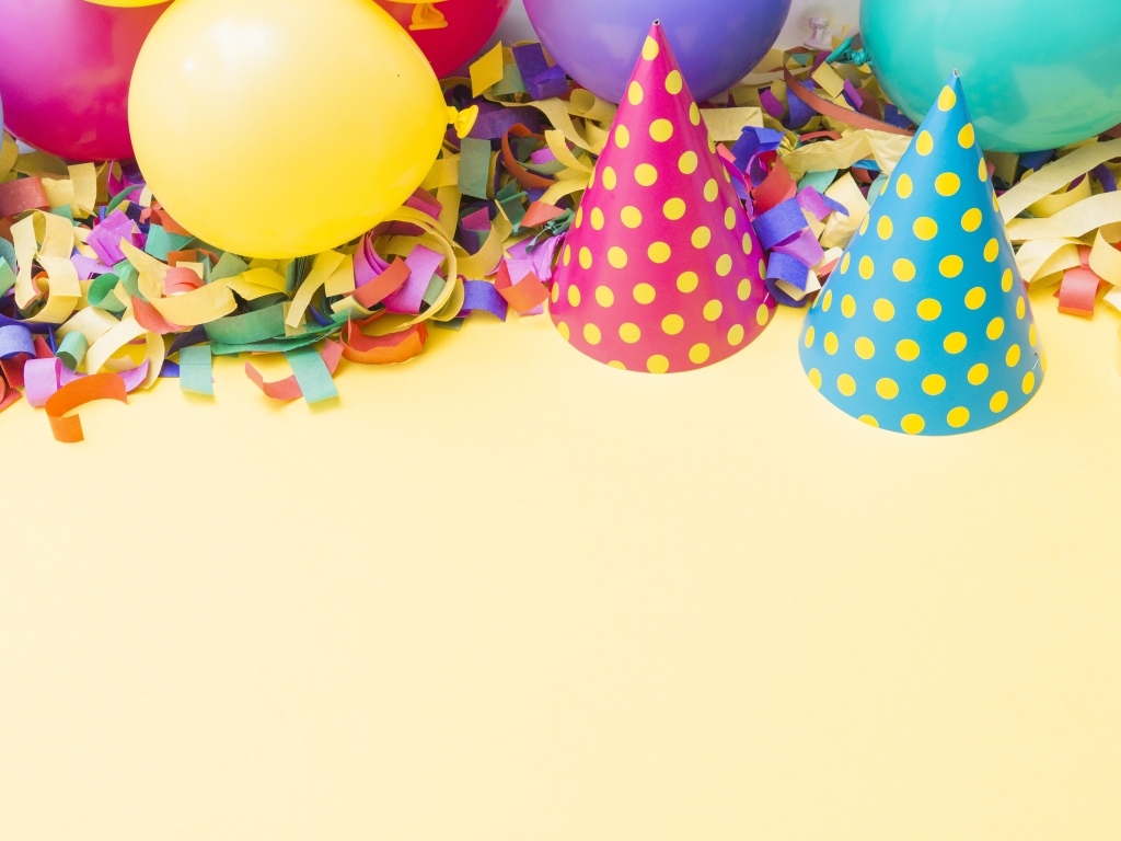 Колпаки, шарики и конфетти на желтом фоне