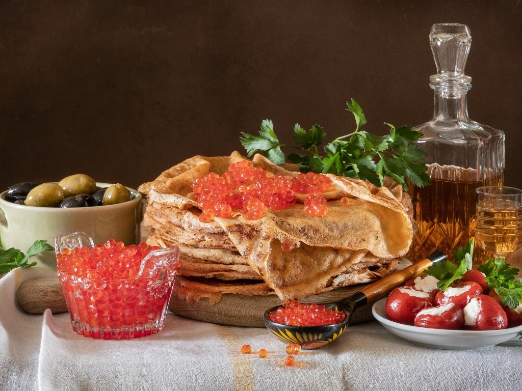 Блины на столе с икрой, маслинами и бутылкой спиртного на Масленицу