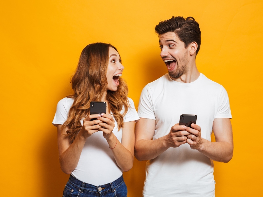 Счастливые парень и девушка с мобильными телефонами