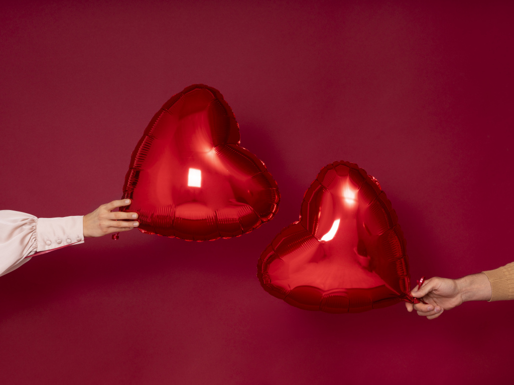 Два воздушных шара в форме сердца на красном фоне