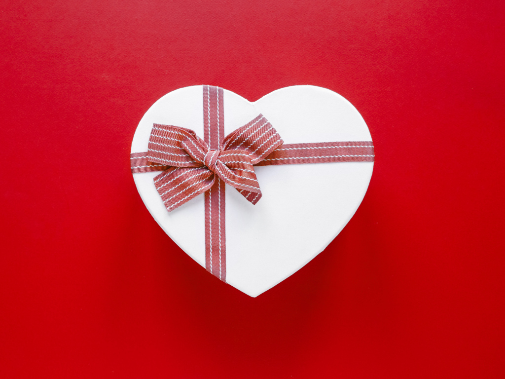 Белая коробка в форме сердца с бантом на красном фоне
