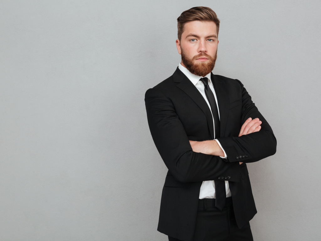 Деловой стильный мужчина в черном костюме на сером фоне