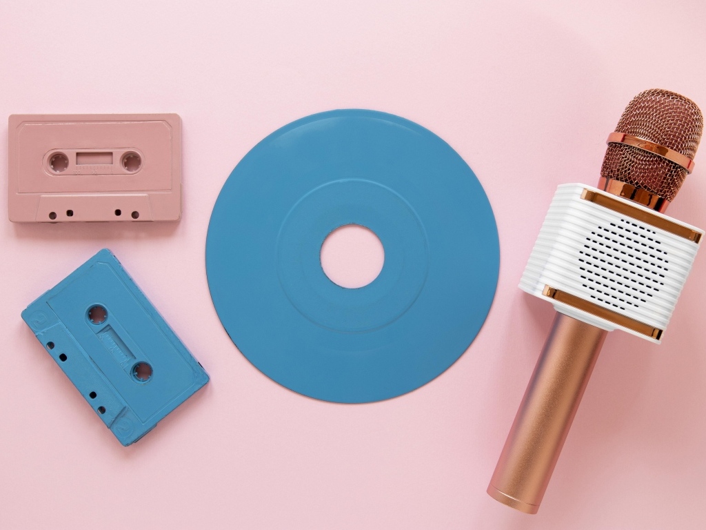 Две кассеты, микрофон и пластинка на розовом фоне