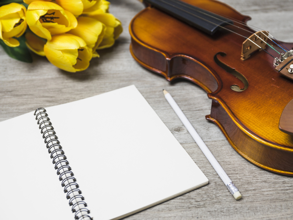 Скрипка, блокнот и желтые тюльпаны на столе