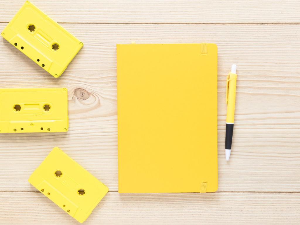 Желтый блокнот с ручкой и кассетами на столе