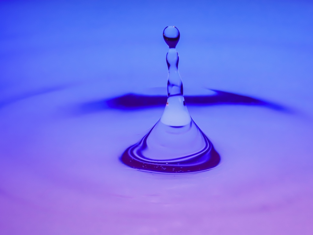 Брызги в воде на фиолетовом фоне