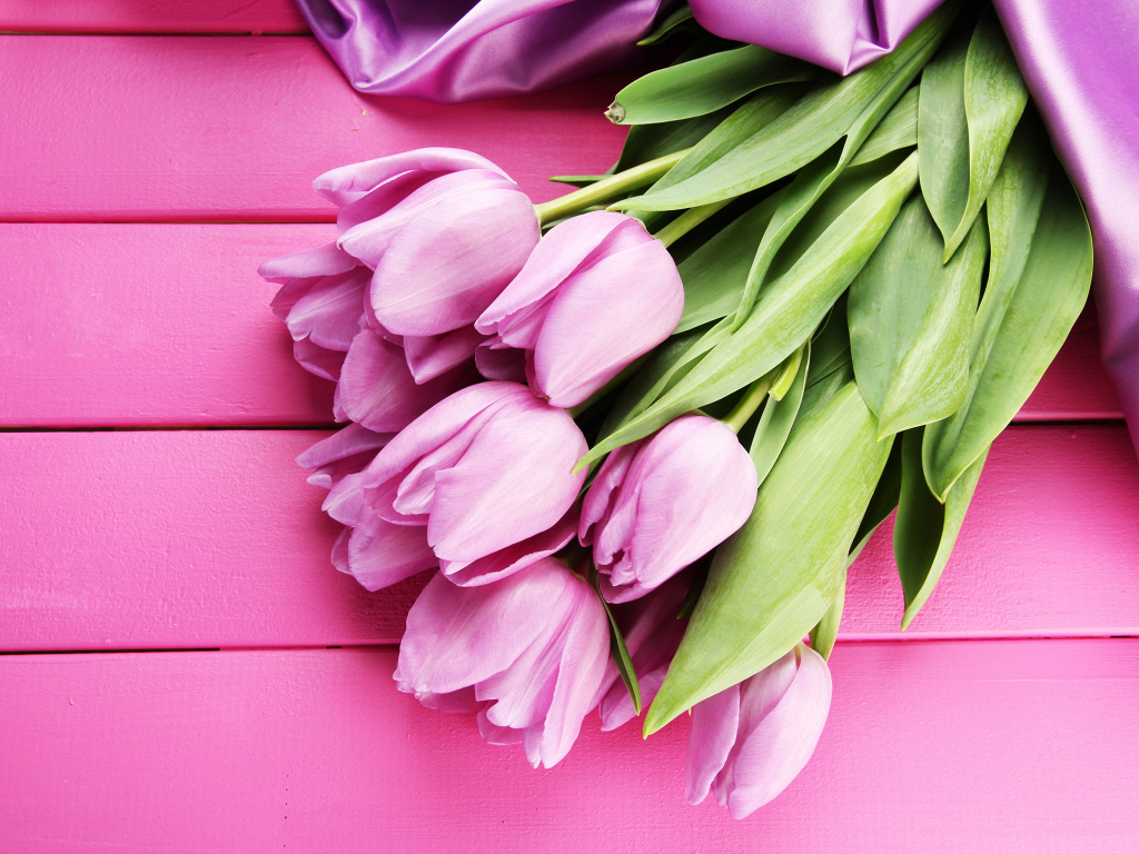 Красивый букет тюльпанов с лентой на розовом столе