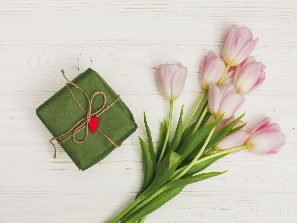 Букет розовых тюльпанов на столе с подарком