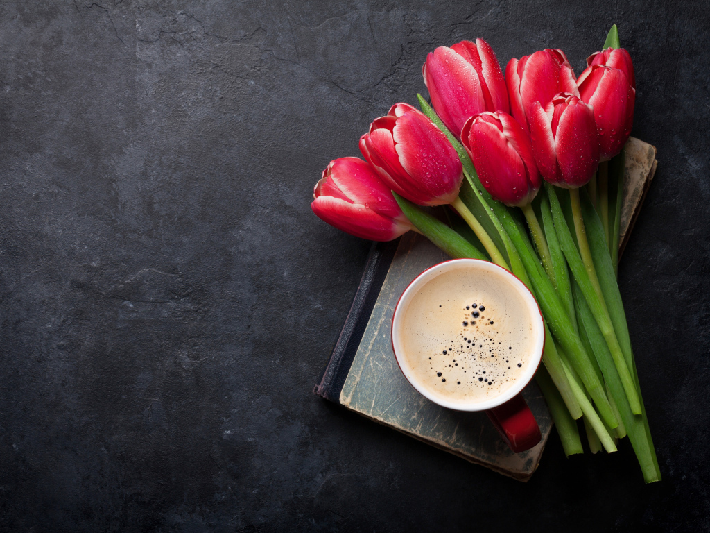 Букет красных тюльпанов с чашкой кофе на черном столе