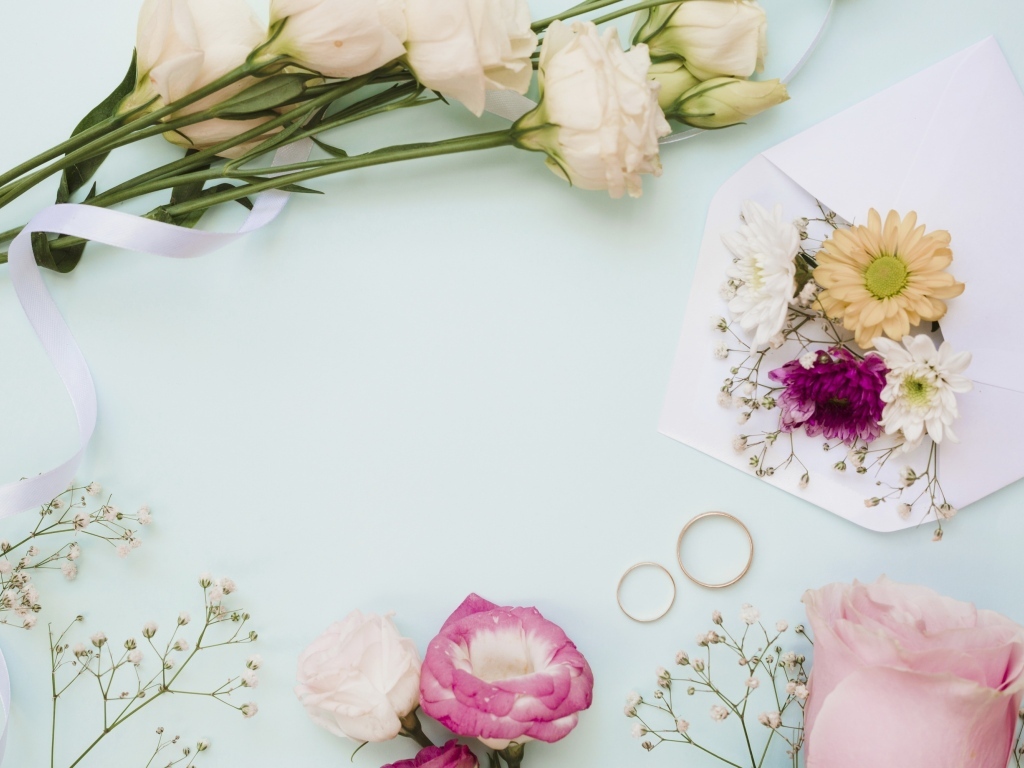 Цветы на голубом фоне с конвертом и обручальными кольцами