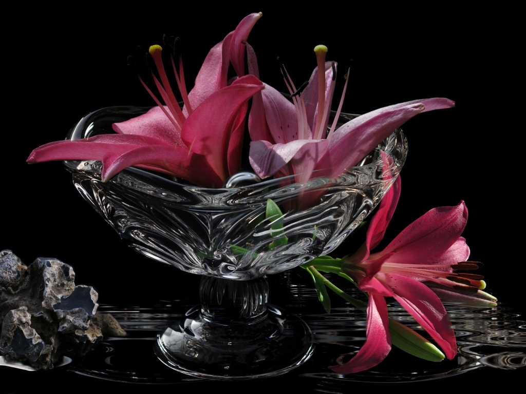 Розовые лилии в стеклянной вазе на столе