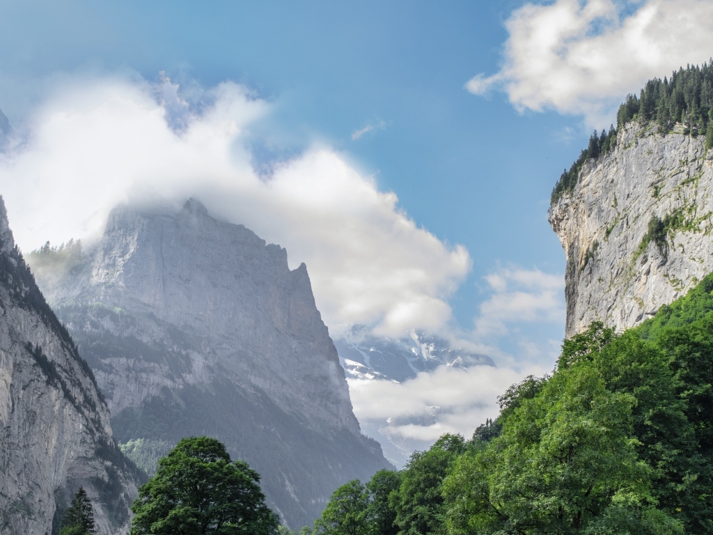 Высокие покрытые зеленью горы в белых облаках