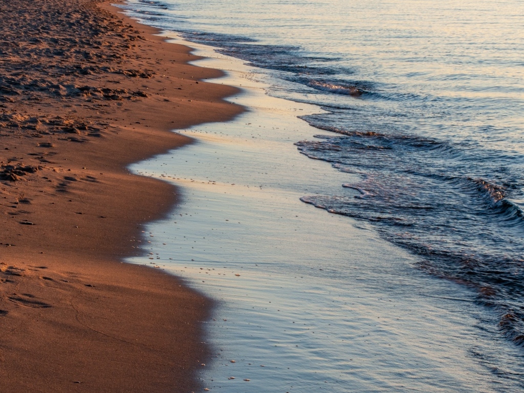 Спокойное море на морском песке на рассвете