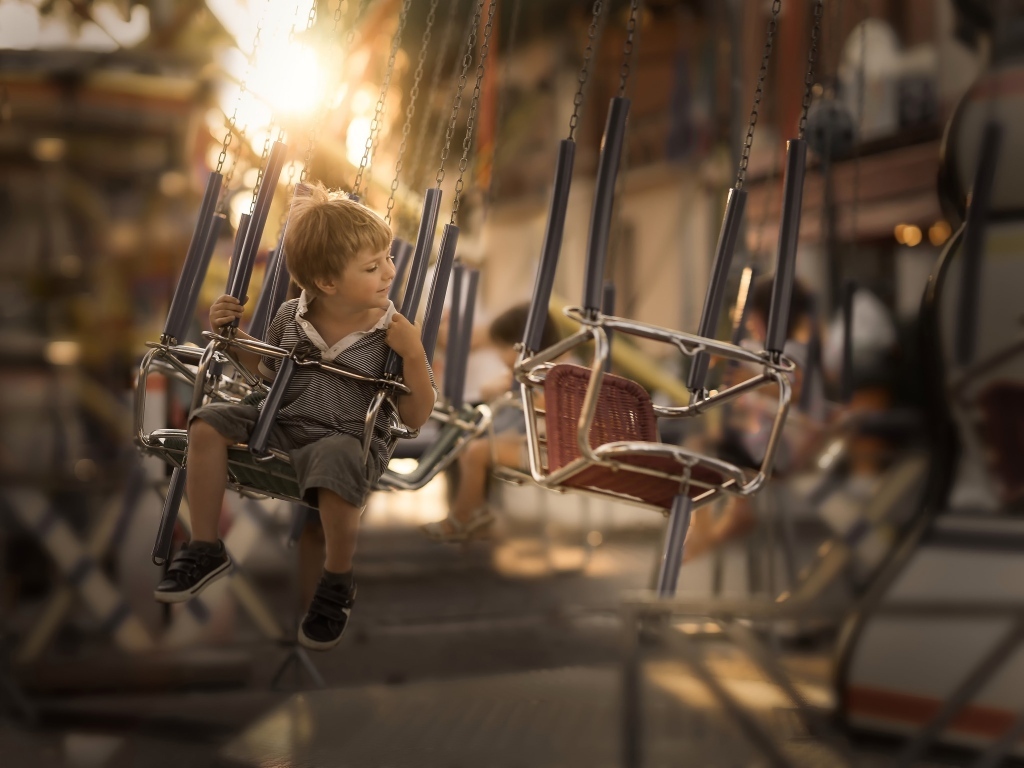 Маленький мальчик катается на каруселях
