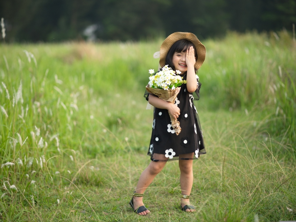 Девочка азиатка в шляпе с букетом цветов