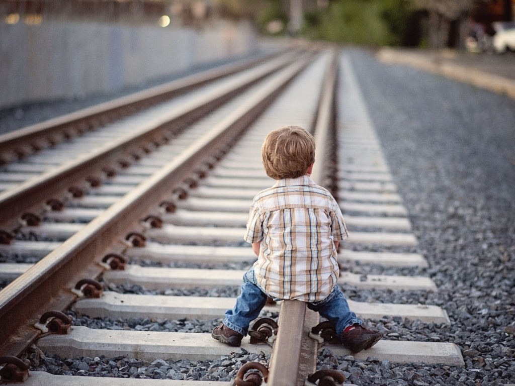 Мальчик сидит на железнодорожных рельсах