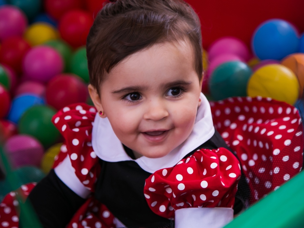 Кареглазая девочка в бассейне с шариками