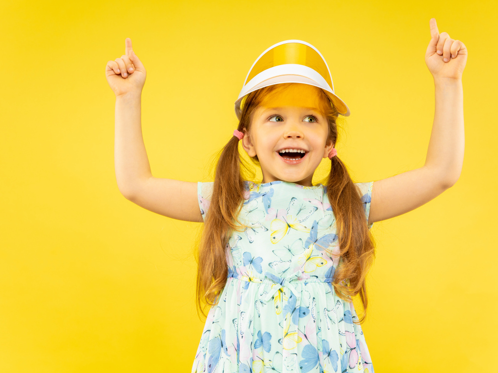 Веселая девочка в платье на желтом фоне