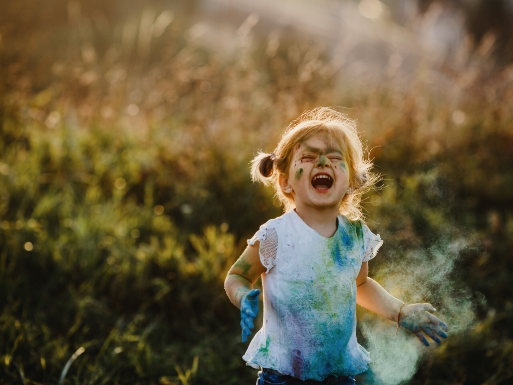 Веселая девочка в краске на улице